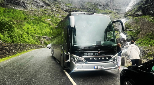 Turbuss fra Geilo Turbusser ved en foss, med passasjerer