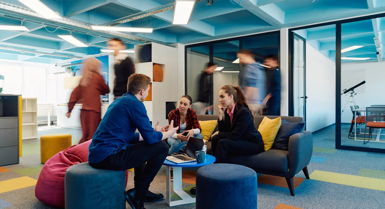 An open plan office where small groups are working together on sofas and low seating.