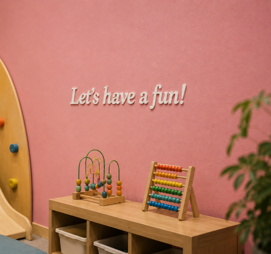 Children's play area with wooden abacus, bead maze toys on shelf under wall text 'Let's have a fun!'