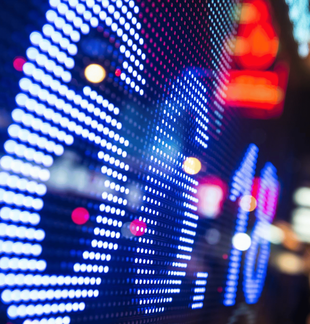 Nahaufnahme einer digitalen Anzeigetafel mit hellen, blauen LEDs, die den Prozentsatz 0,1% anzeigen, verschwommene bunte Lichtpunkte im Hintergrund.