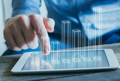 Eine Person berührt mit dem Finger einen Tablet-Bildschirm, auf dem eine transparente, digitale Balkendiagramm-Grafik angezeigt wird.