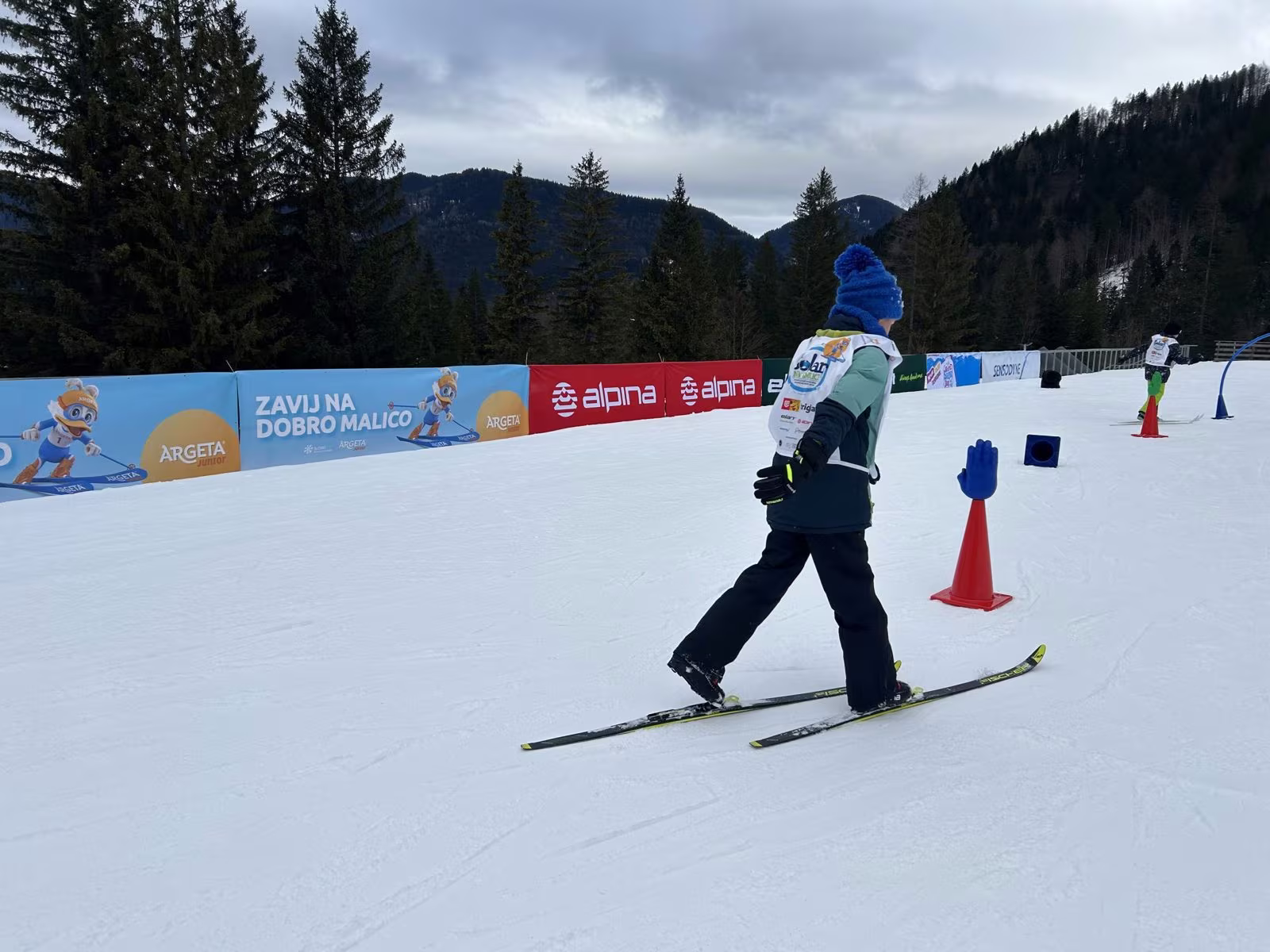 Otrok smuča med stožci na smučišču