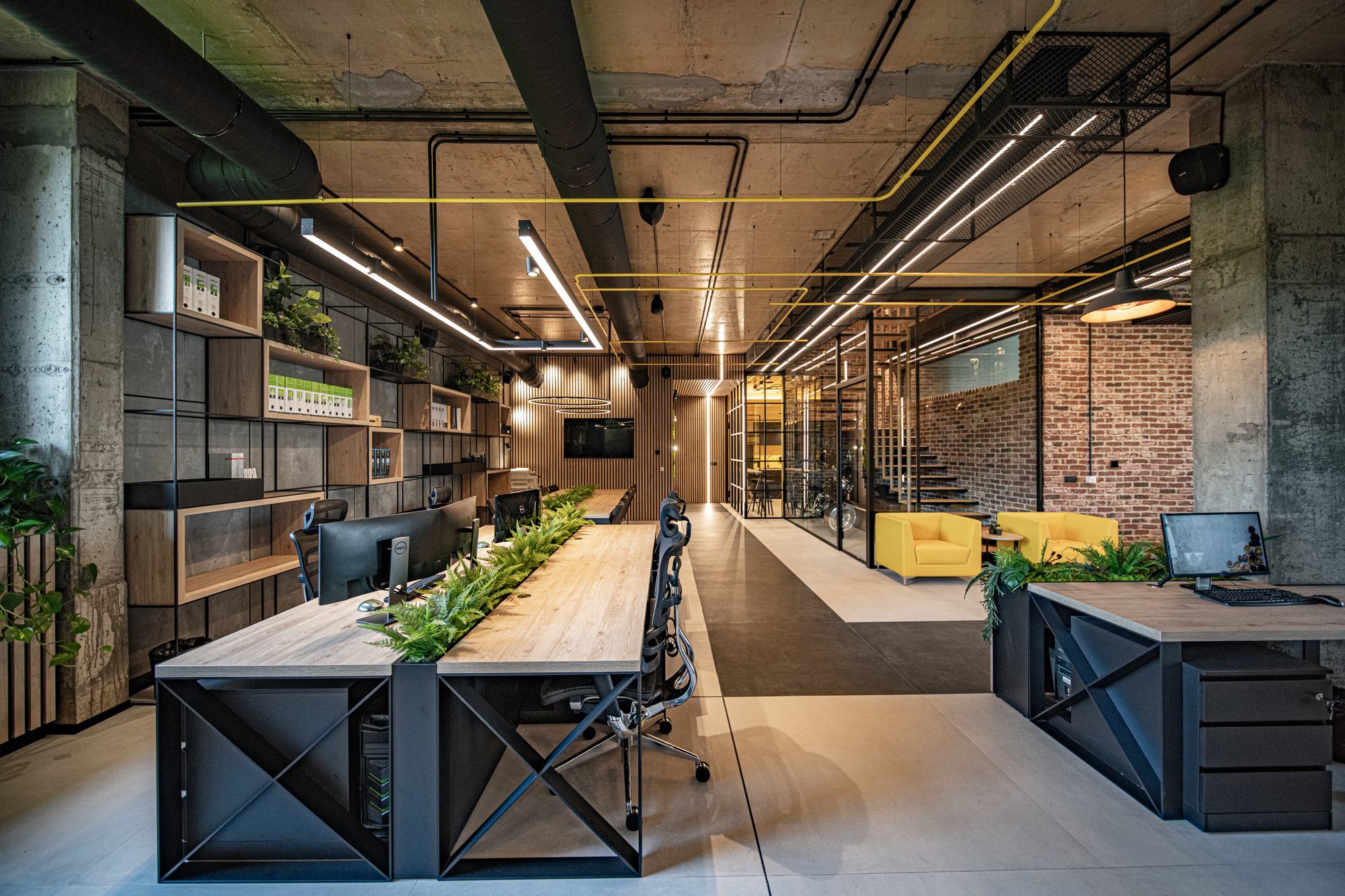 Comfort Partners Headquarters — the shared desk under linear lighting, shelving along the wall
