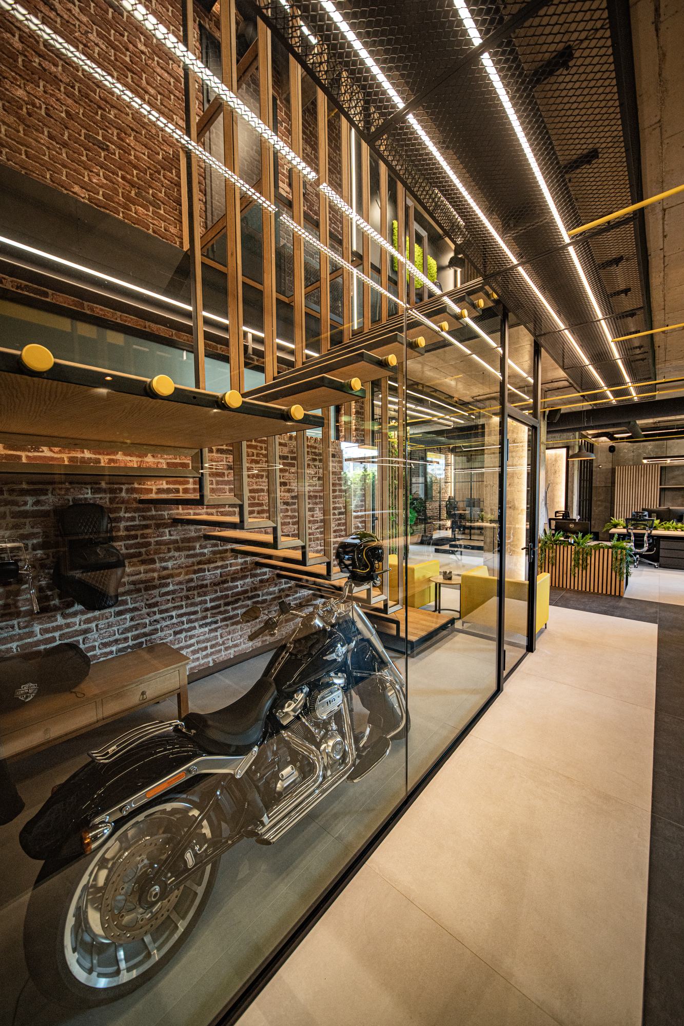 Comfort Partners Headquarters — the motorcycle behind glass beside the slatted timber screen