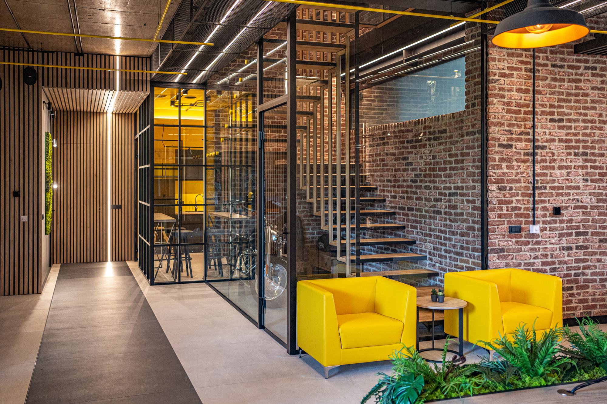 Comfort Partners Headquarters — corridor past the meeting room, yellow armchairs and the stair beyond