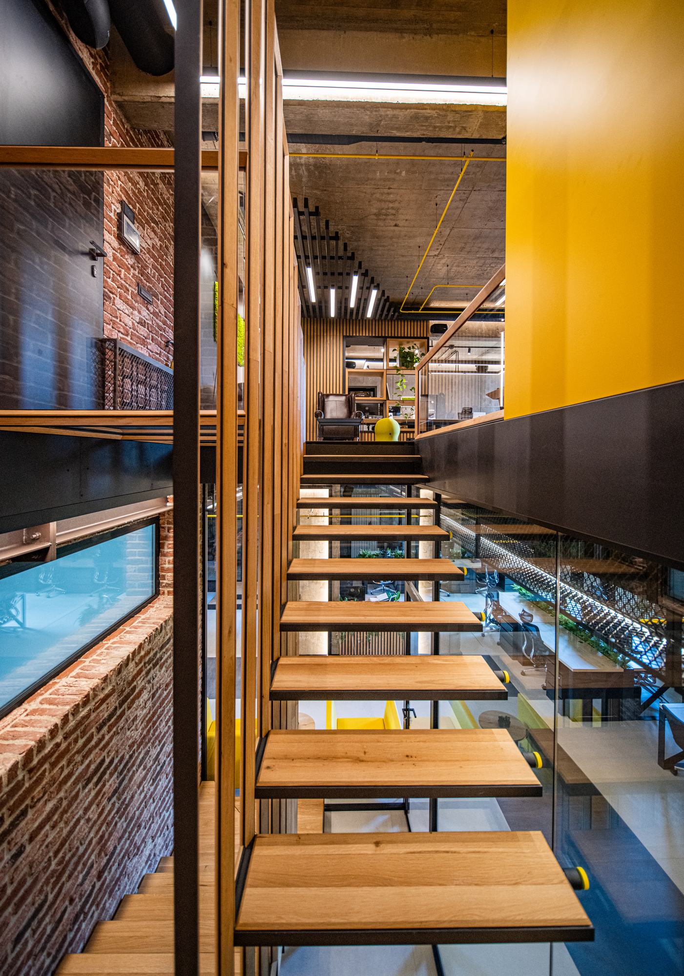 Comfort Partners Headquarters — oak treads of the suspended stair against the yellow wall