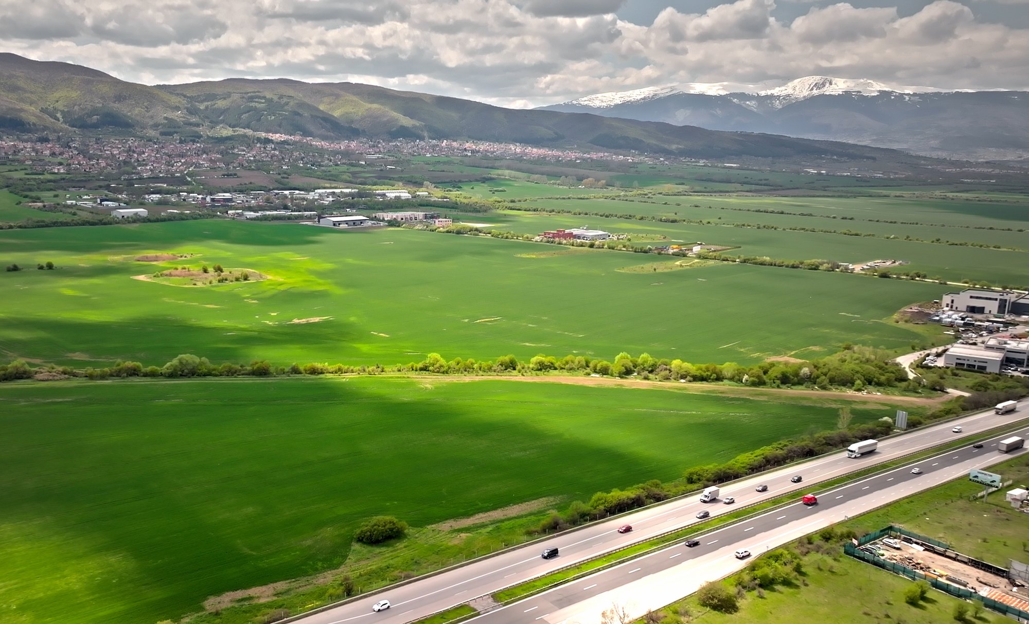 Dolni Lozen — looking across the land towards the snow-covered mountains, the motorway along the near edge