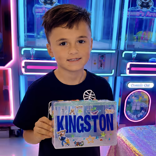 A boy holding the keepsake box he decorated, his name spelled out in blue letters