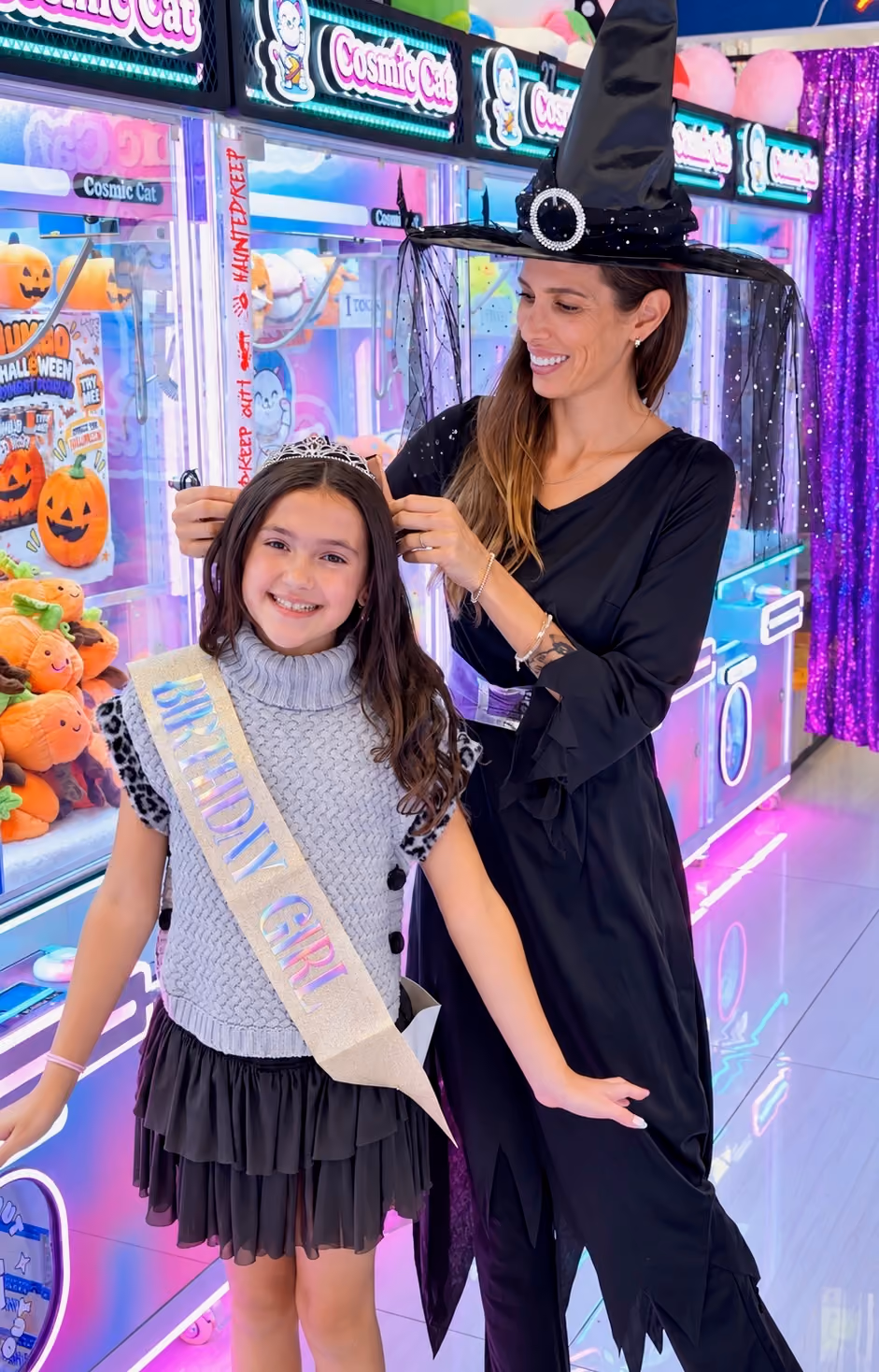 A Cosmic Cat team member places a sparkly crown on a smiling birthday girl wearing a Birthday Girl sash