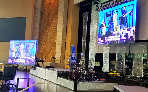 A large screen with a band playing in front of it.