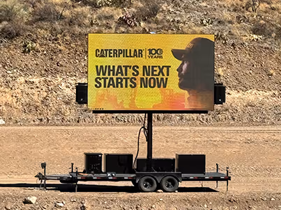 Mobile digital billboard on trailer displaying Caterpillar's 100 years ad with slogan What’s Next Starts Now.