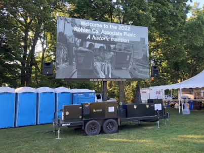 Outdoor event screen reads welcome to the 2022 Kohler Co. Associate Picnic in a grassy park area.