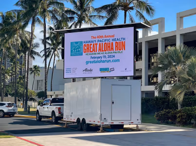 Outdoor digital sign promoting the 40th Annual Hawaii Pacific Health Great Aloha Run on a white trailer.