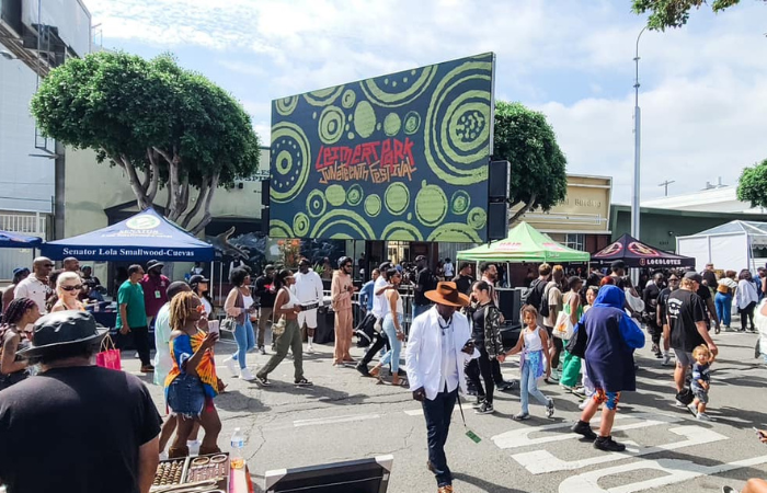 Crowd walking and mingling at an outdoor festival with tents and a large LetliveArt Festival sign.