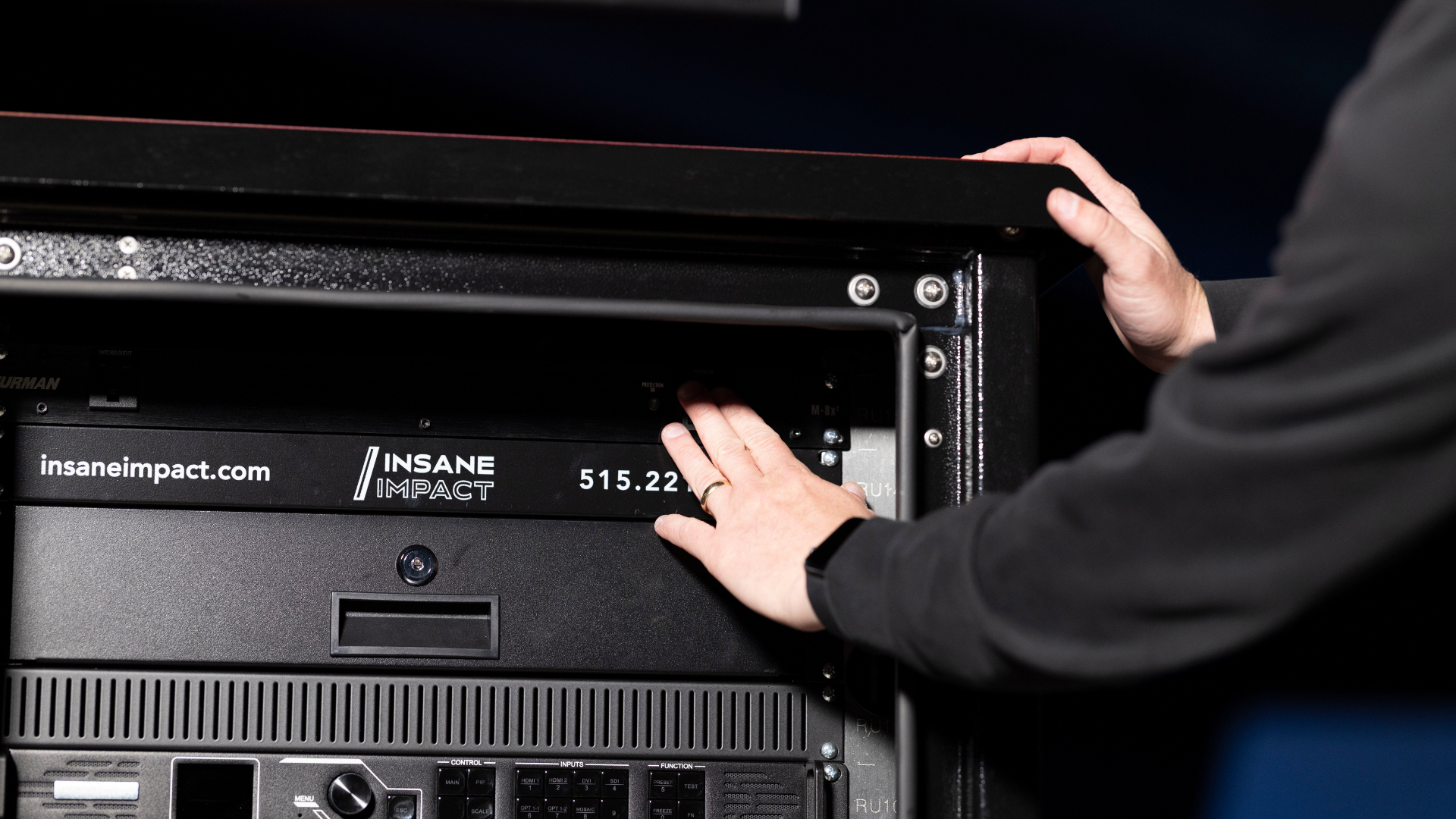 Hands adjusting equipment labeled insaneimpact.com and INSANE IMPACT in a metal rack.
