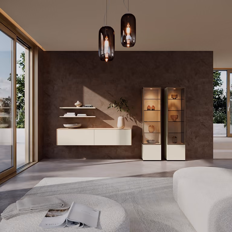 Modernes Wohnzimmer mit großen Fensterfronten, zwei hängenden Glaslampen, einer dunkelbraunen Wand mit schwebendem Sideboard und weißen Vitrinenschränken, auf denen dekorative Vasen und Schalen stehen.