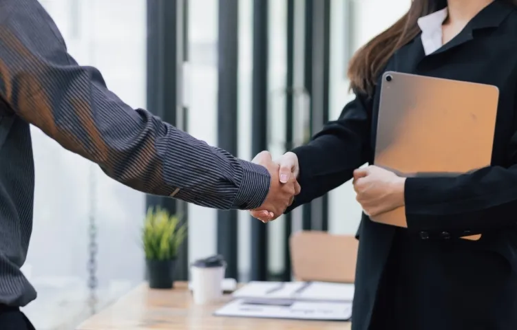 Two professionally dressed people, one male and one female, shaking hands