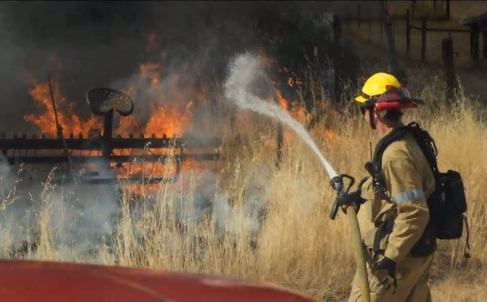 A Lincoln fire fighter working a grass fire hose line