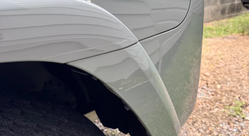 Close-up of a fixed area on a vehicle's light gray fender above the tire.