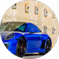Blue sports car parked in front of a beige building with multiple windows.