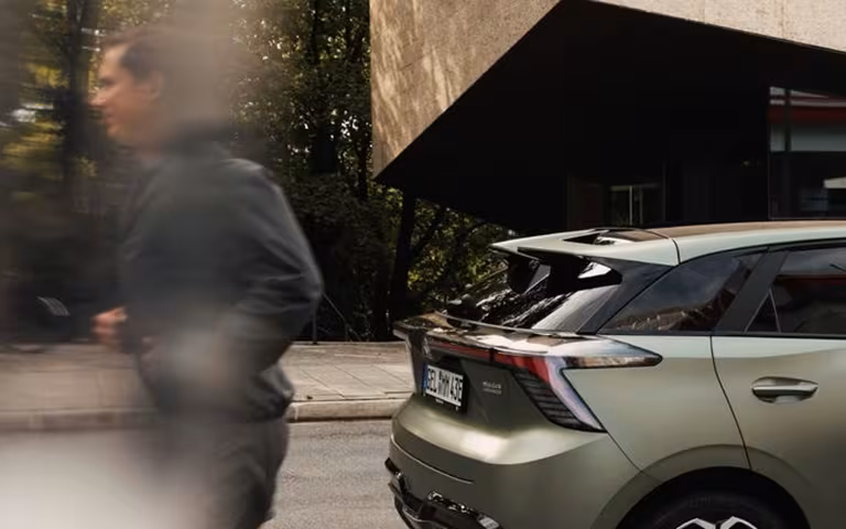 SUV verde estacionado en la ciudad, vista trasera, con un peatón cruzando en primer plano