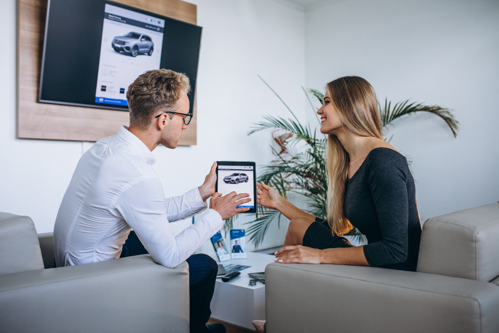 Hombre y mujer en una sala de exposición de automóviles usando una tablet