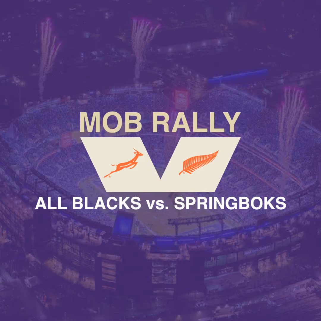Night aerial view of a packed stadium with fireworks above and graphic text saying MOB RALLY, ALL BLACKS vs. SPRINGBOKS with logos of a springbok and a silver fern.