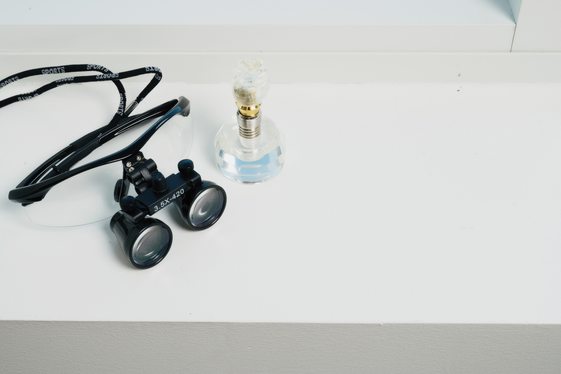 Dental loupes and a dental implant model displayed on a countertop