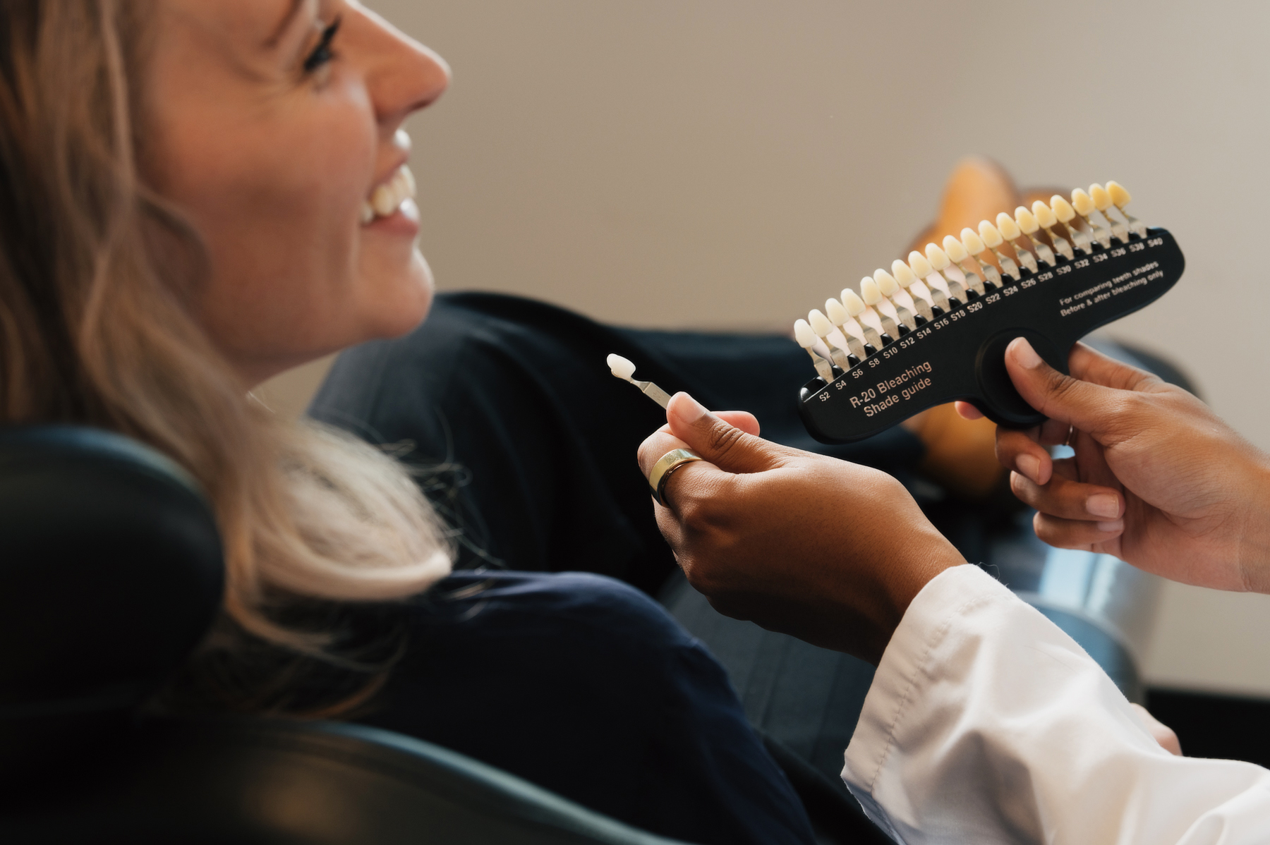 Dentist showing a smiling patient a tooth shade guide during a teeth whitening consultation