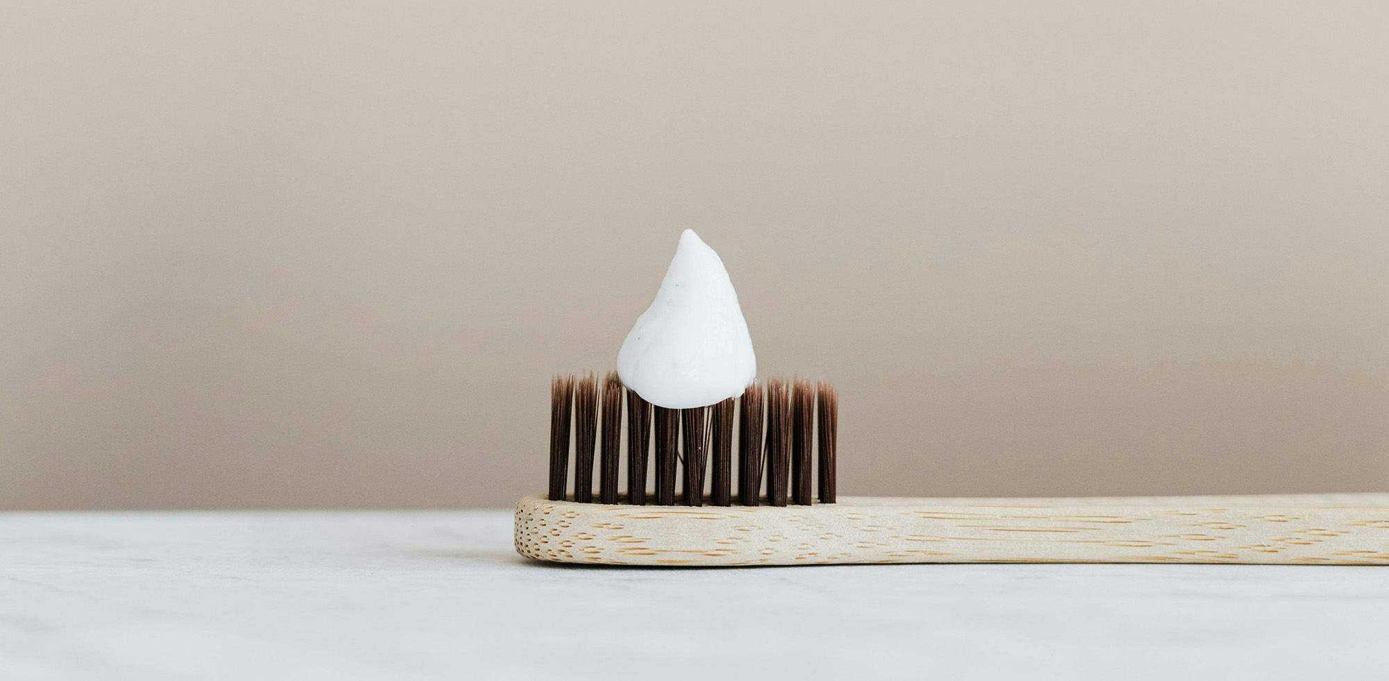 Close-up of toothpaste on a wooden-handled toothbrush