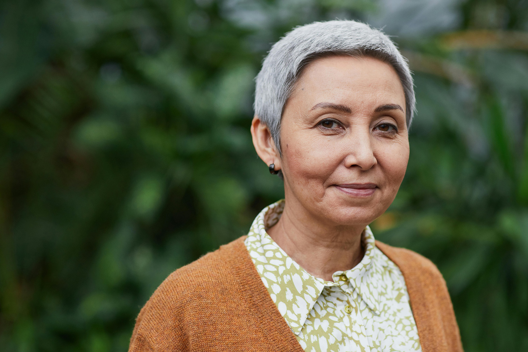 Portrait of an older woman with short gray hair smiling gently outdoors