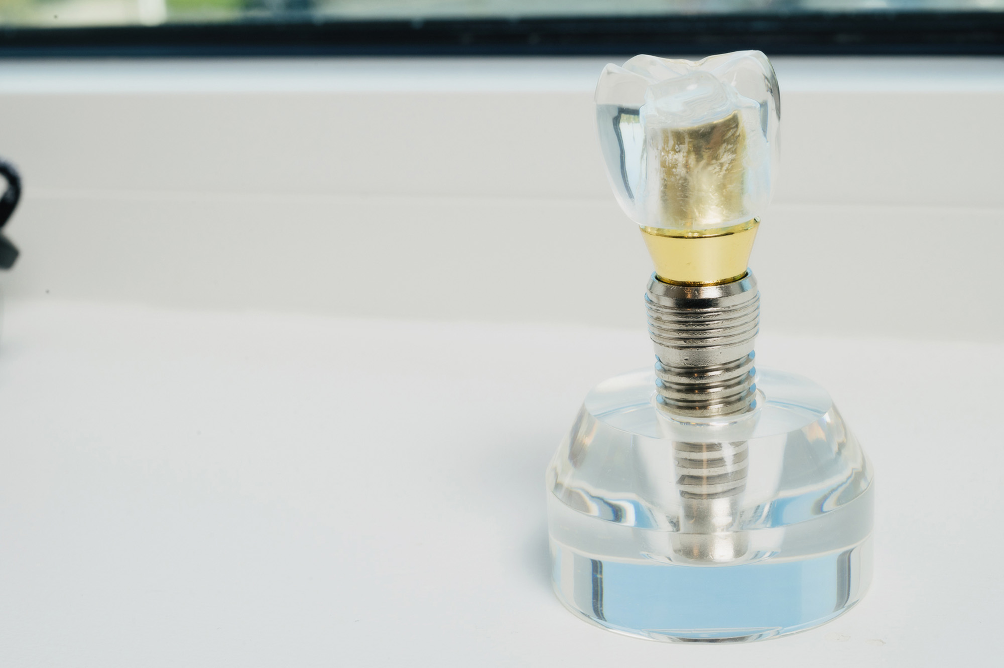 Model of a dental implant with crown displayed on a countertop