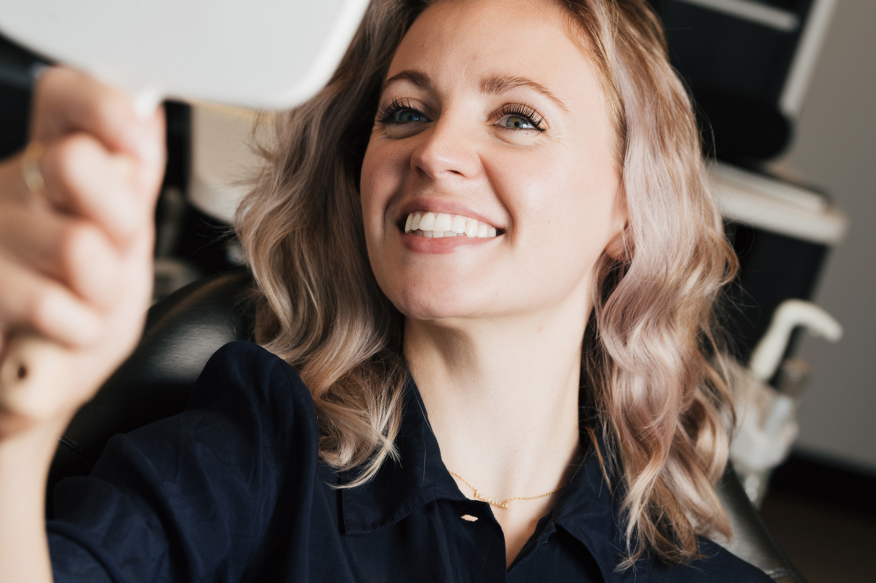 Smiling woman taking a selfie while reclined in a dental treatment chair