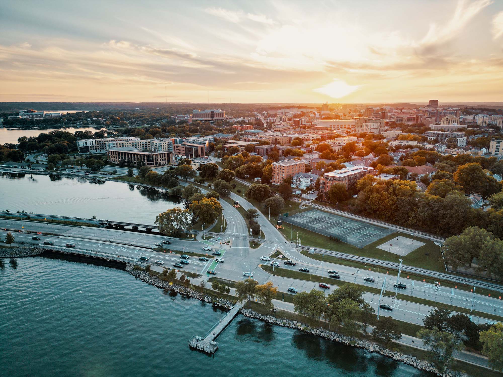 Aerial view of downtown Madison, Wisconsin at sunset, with a causeway between two lakes leading into the city skyline