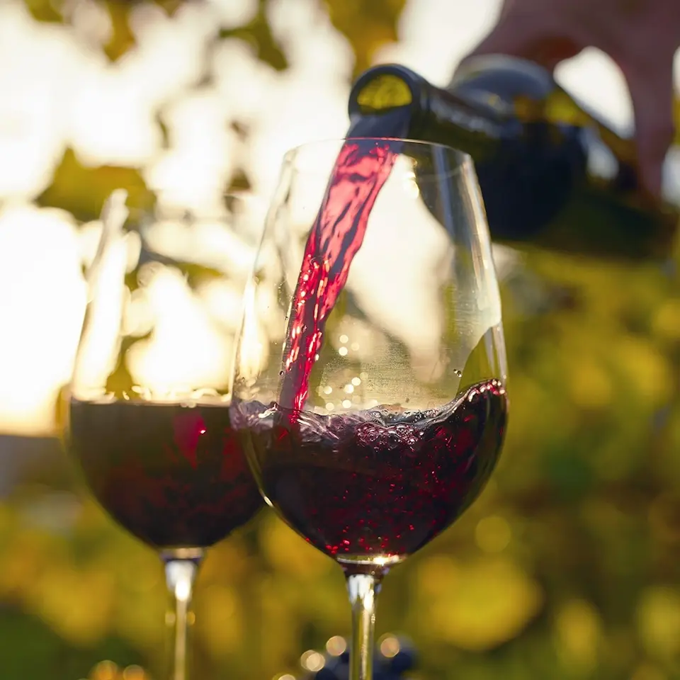 Red wine being poured into two glasses