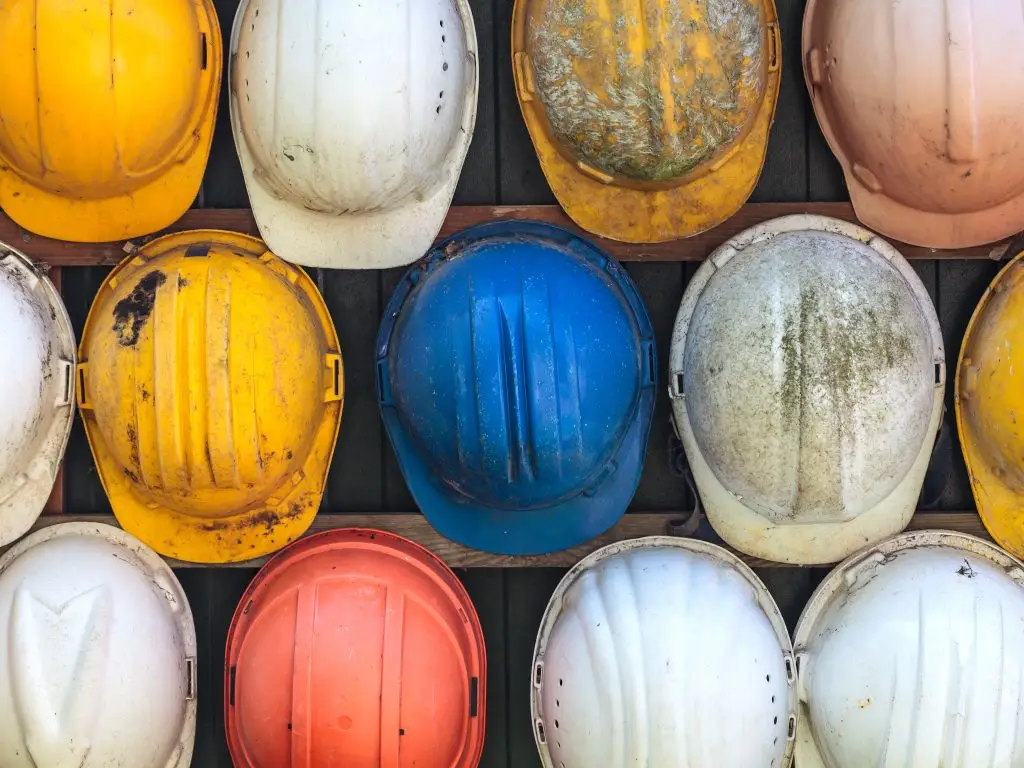 Rows of worn hard hats in different colours