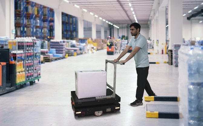 Peer AMR moving a palletized load through a facility alongside an operator