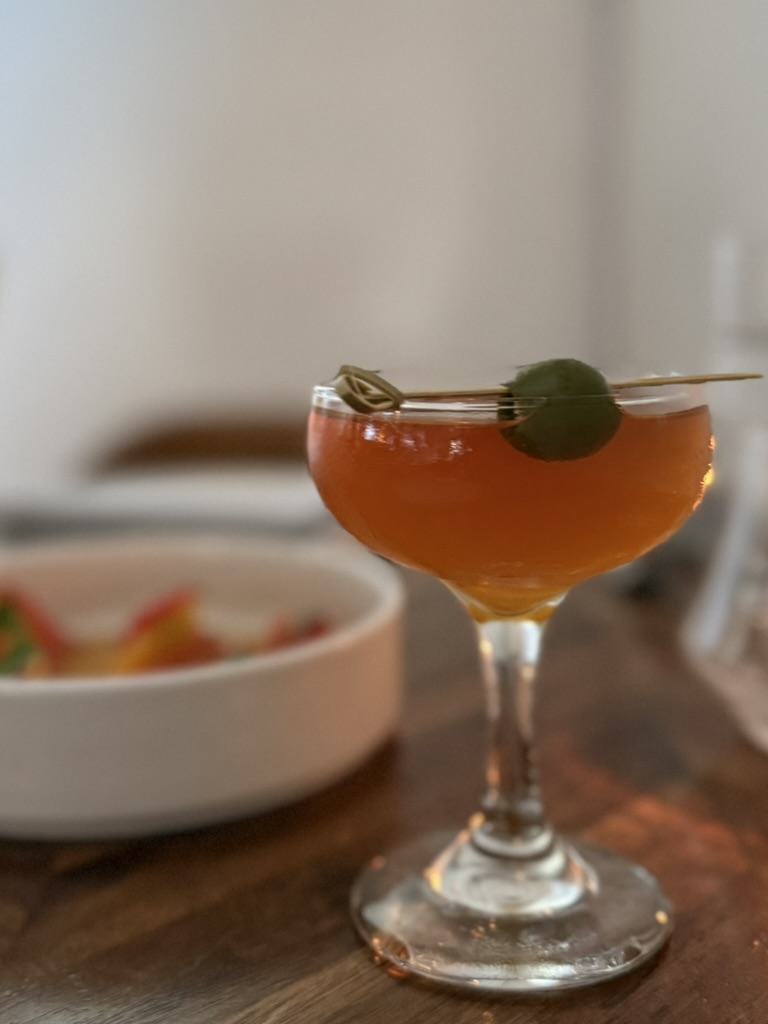The Adobo Martini at Musang, Seattle, garnished with an olive