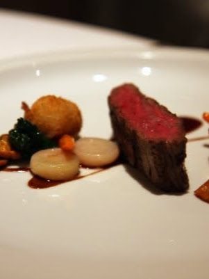 Slices of rare grilled beef with a crisp golden sphere of bone marrow pudding, glazed onions, chanterelles and a dark bordelaise sauce