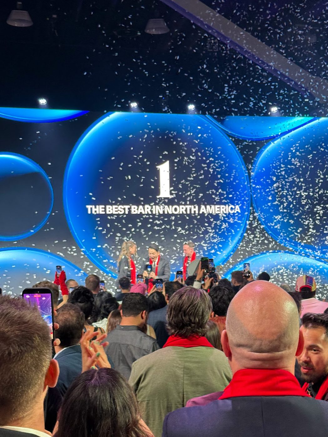 Confetti falling over the stage beneath a screen reading number one, The Best Bar in North America, as the winning team is interviewed
