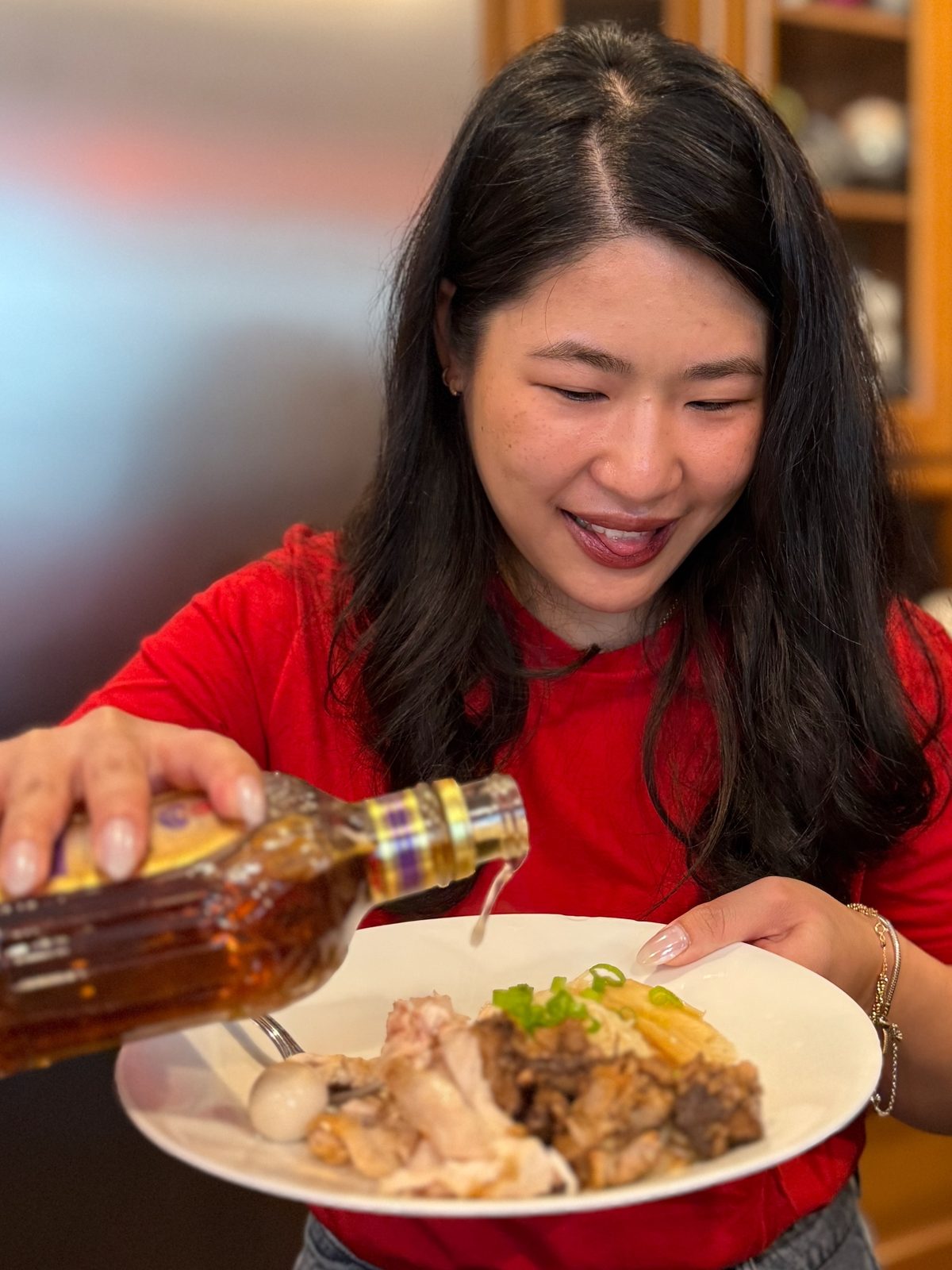 A guest in red pouring a little whiskey over a plate of Tsa Misua at the table