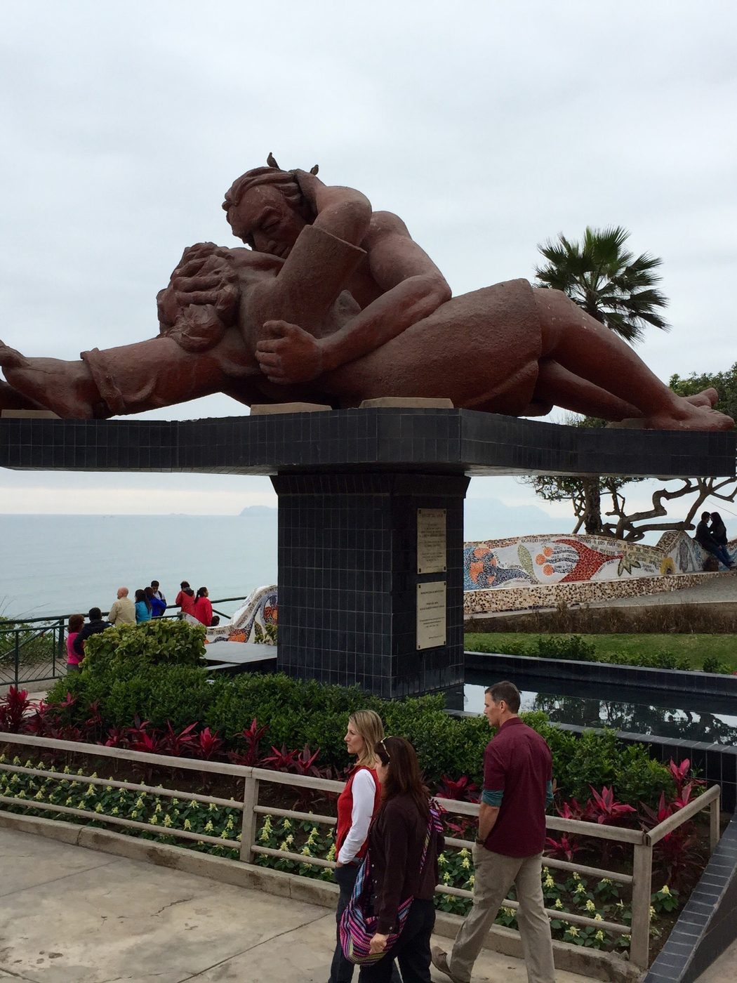 El Beso, a large red sculpture of a kissing couple, on the Miraflores clifftop with the flat grey Pacific behind it.