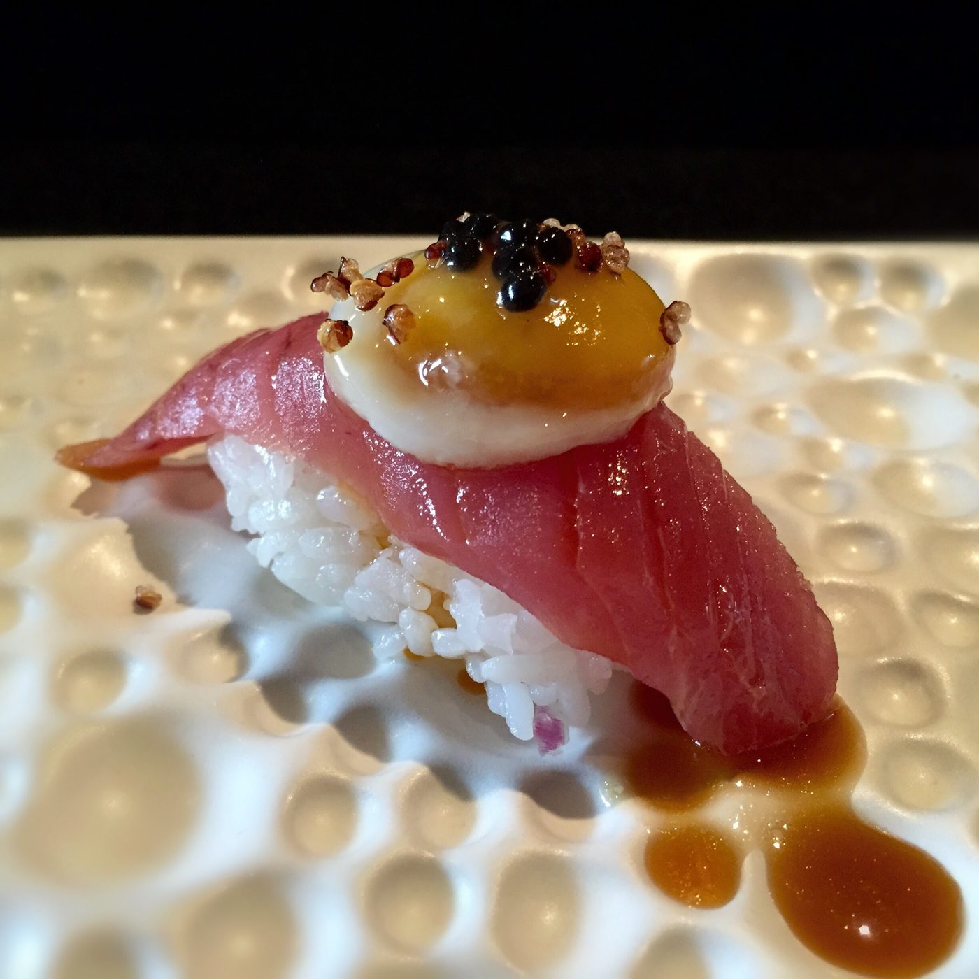 A tuna nigiri topped with a quail egg yolk, black caviar and popped quinoa.