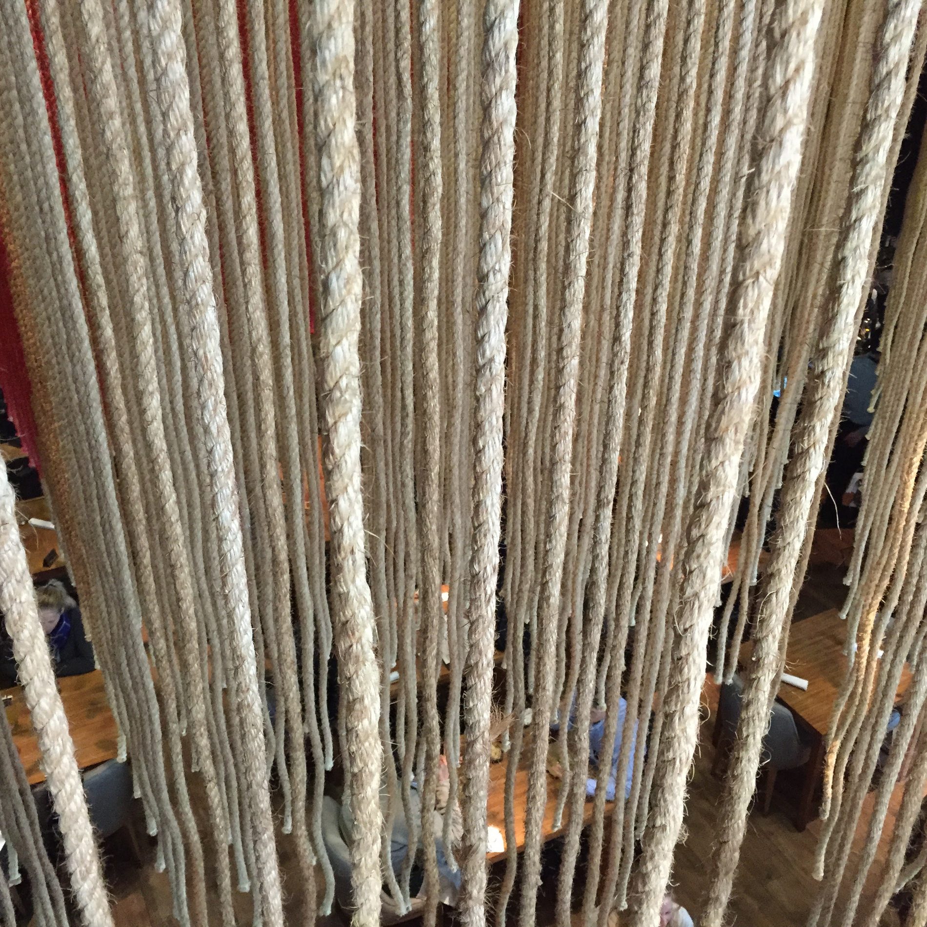 Looking down through a screen of hanging ropes from the upstairs sushi counter at Maido into the dining room below.