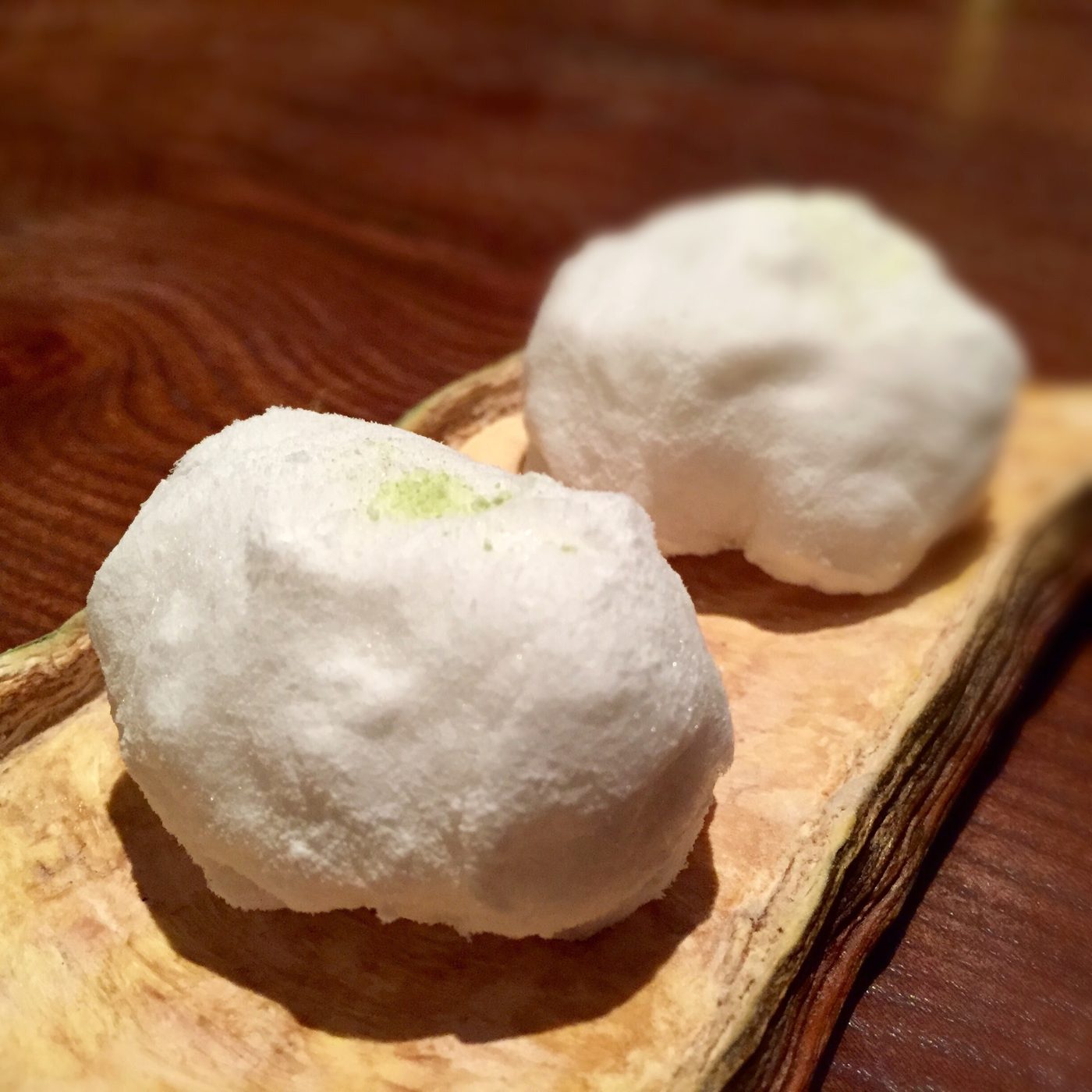 Two irregular white spheres, powdery and slightly collapsed, resting in a long pale trough laid across the table.