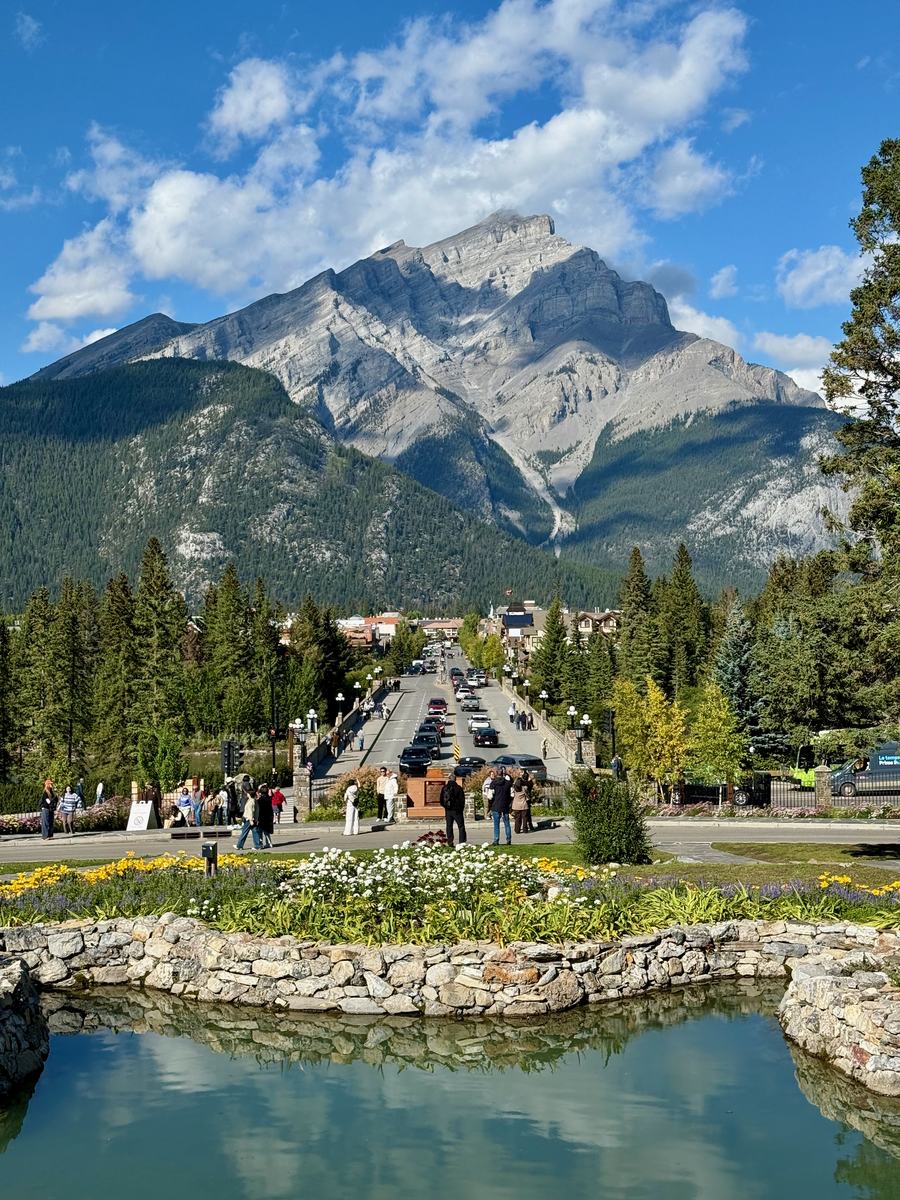 Banff Avenue running straight toward Cascade Mountain, seen from the gardens across the river