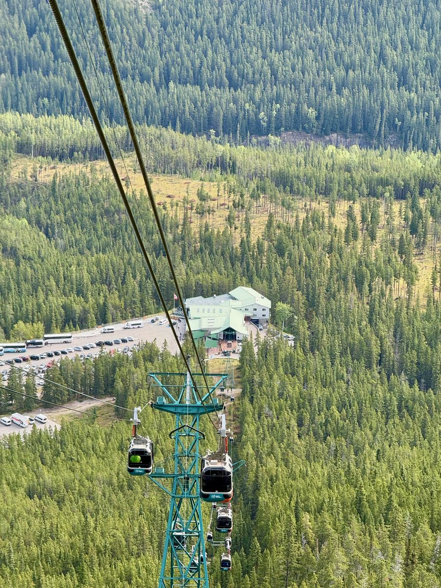 Looking straight down the gondola cable from a cabin, with other cabins below and the lower terminal at the foot of the line