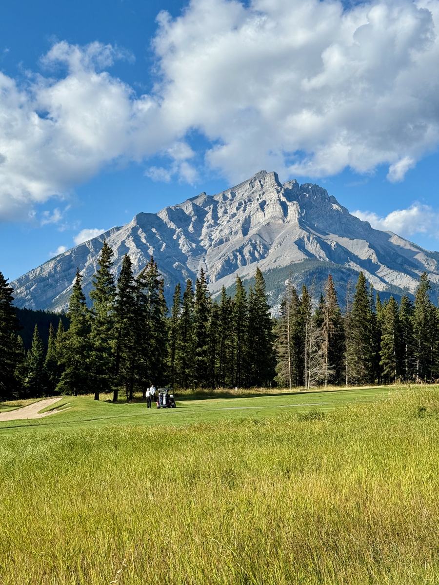 Two golfers and a cart on a fairway with Cascade Mountain standing over the course