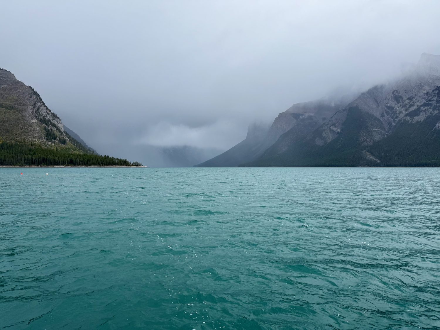 Lake Minnewanka under heavy storm cloud, the water stretching away between dark mountains