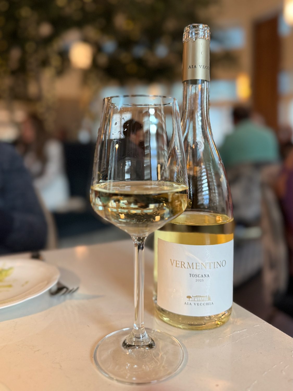A poured glass of white wine beside its bottle, an Aia Vecchia Vermentino from Tuscany